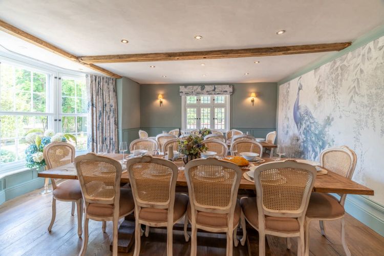 Spacious dining room with a long wooden banquet table and period architectural details, set for a large group celebration.