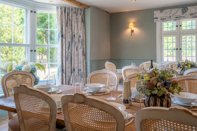 Spacious dining room with a long wooden banquet table and period architectural details, set for a large group celebration.
