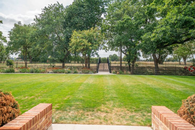 A landscaped garden at Porters Hall featuring a large stone patio, outdoor dining furniture, and a barbecue area for guest use.