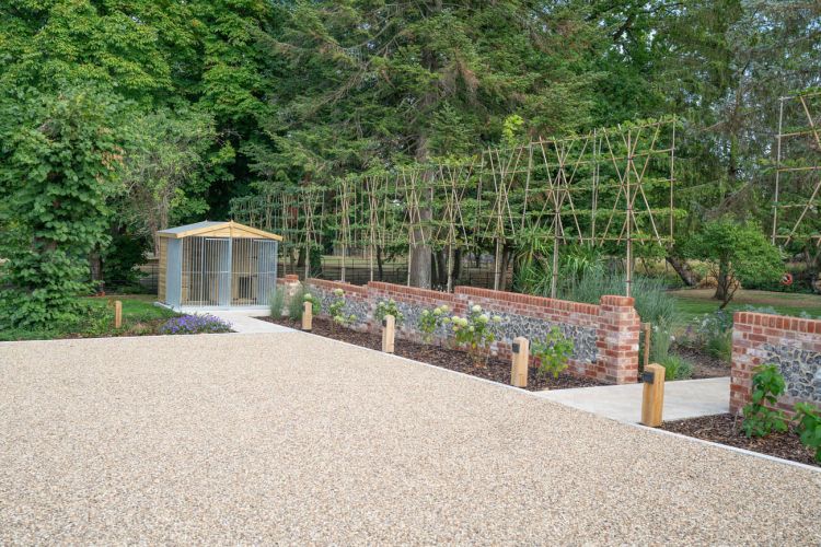 A landscaped garden at Porters Hall featuring a large stone patio, outdoor dining furniture, and a barbecue area for guest use.