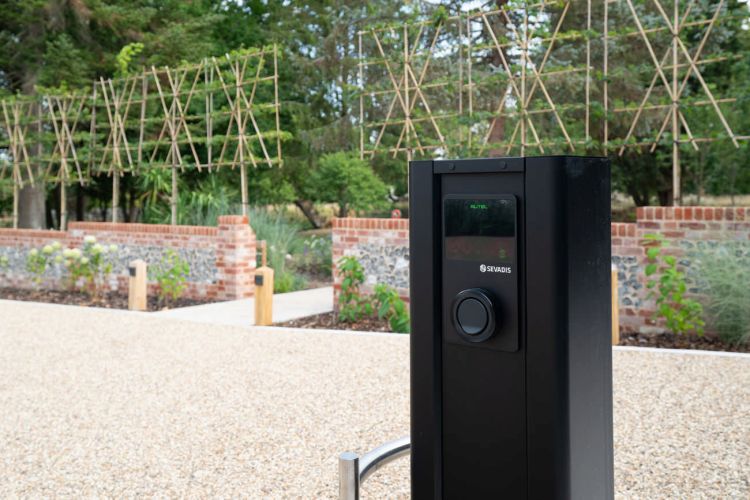 A landscaped garden at Porters Hall featuring a large stone patio, outdoor dining furniture, and a barbecue area for guest use.