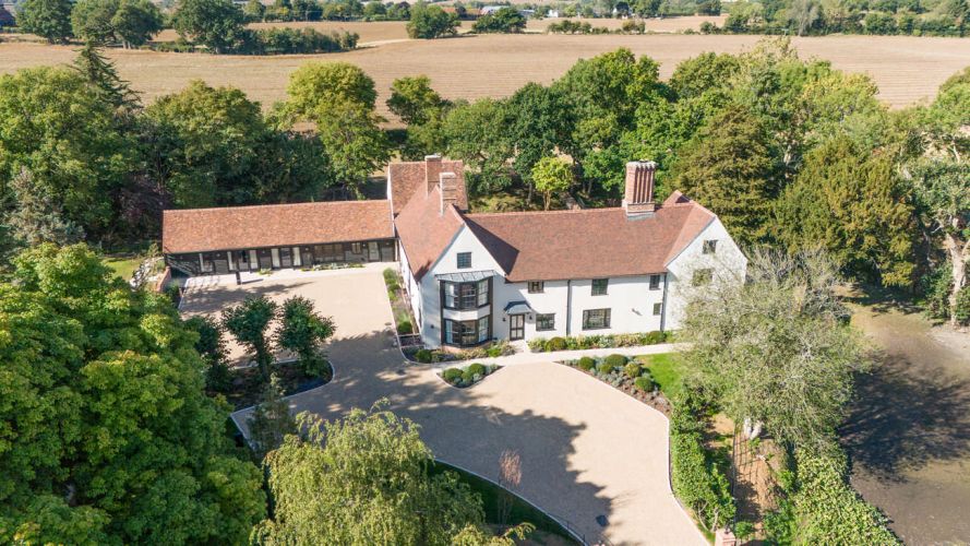 Aerial view of Porters Hall, a historic Grade II listed manor house surrounded by a medieval water moat and lush green Essex countryside