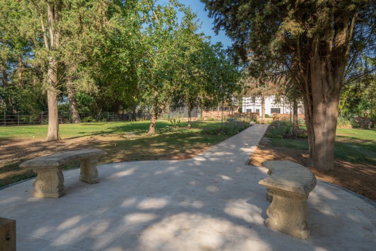 A landscaped garden at Porters Hall featuring a large stone patio, outdoor dining furniture, and a barbecue area for guest use.