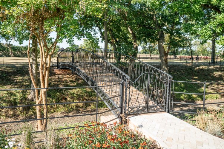 A landscaped garden at Porters Hall featuring a large stone patio, outdoor dining furniture, and a barbecue area for guest use.